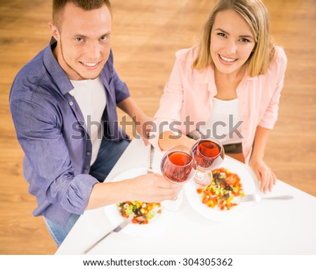 Beautiful family couple having dinner together. They are drinking wine and looking at camera. Top view.