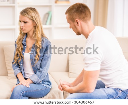Young couple having big trouble in relations. Sad woman sitting back to her husband.
