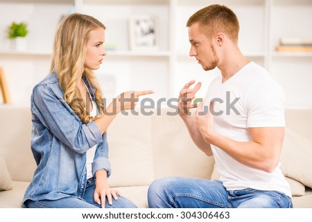 Young couple having disput on a sofa at home.