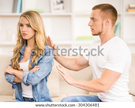 Young couple having big trouble in relations. Angry woman sitting back to her husband.