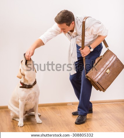 Young businessman is feeding his lovely dog.