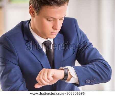 Close-up of young businessman is looking at the watch.
