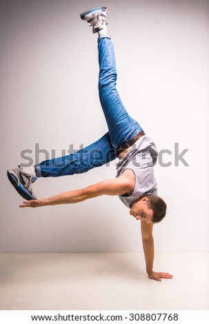 Skilful breakdancer doing moves while performing a handstand over white background.