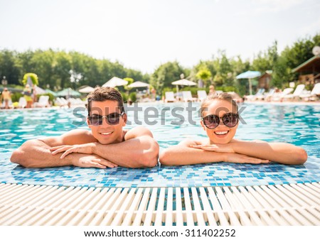 Young couple relaxing in resort swimming pool.