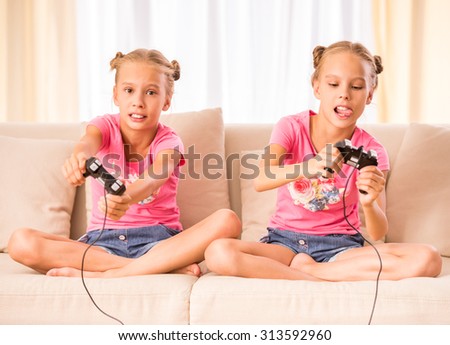 Young twins are playing  video game holding joysticks in hands.