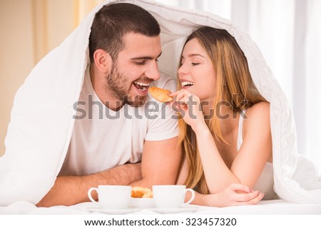 Breakfast in bed. Young happy couple eating breakfast in her bedroom