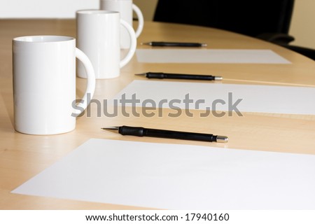 cups pencils and white paper in a meeting room
