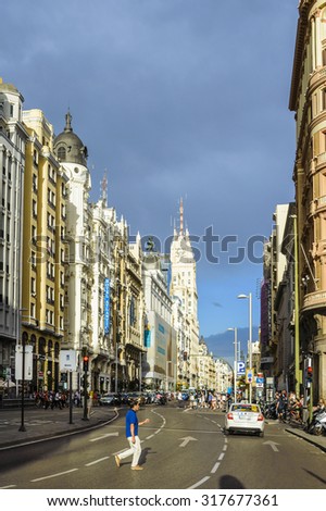 Madrid, Spain - August 31, 2015: A man crosses the street Gran Via in Madrid one summer evening