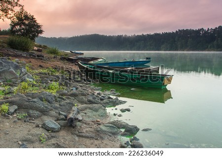 Dawn on the river Otava, Czech Republic. Early morning mist over the river, the boat and the silence around.
