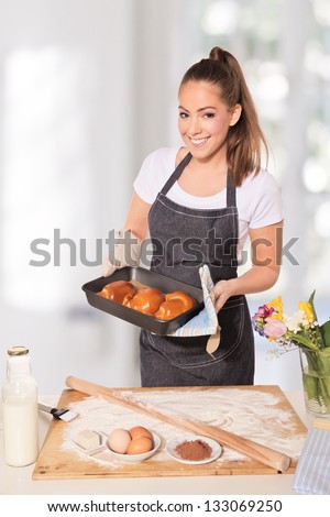Baking woman showing a tray of cookies fresh out of the oven