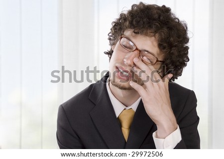 Man in business suit massaging his eye to relieve his headache