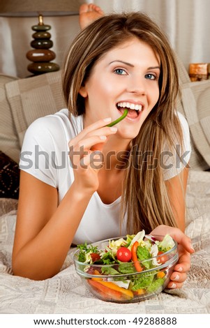 Young beauty woman couch in the bed and eating salad