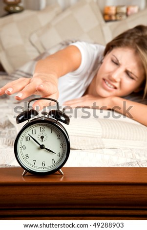 Young beauty woman couch in the bed and turning off the alarm clock
