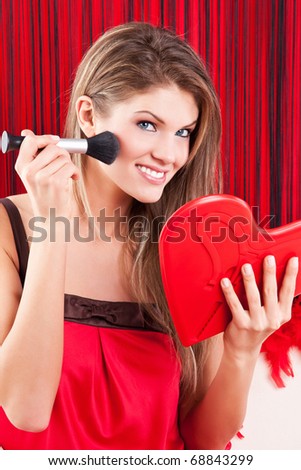 Portrait of a cute young woman holding a red heart mirror