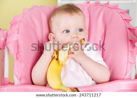 Hungry baby girl eating a banana
