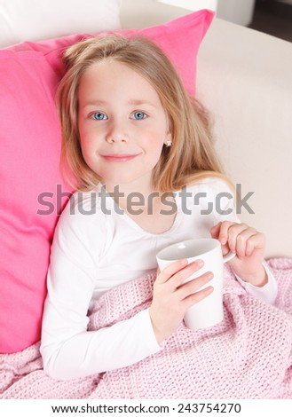 Sweet little girl drinking tea in the bed