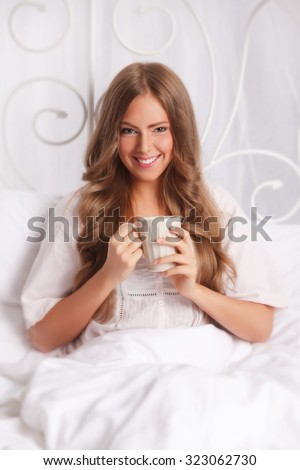 Beautiful woman relaxing in the bed with a cup of tea
