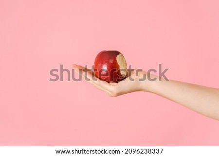 A bitten red apple in an open female palm on a pink background Stock foto © 
