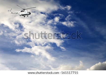 Helicopter in sunny blue sky with clouds