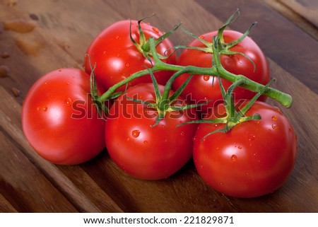 Bunch of fresh tomatoes with water drops on wooden table
