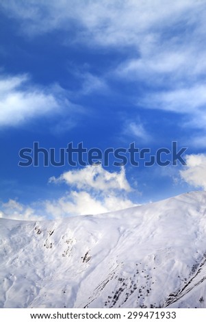Off-piste slope and blue sunlight sky with clouds. Caucasus Mountains, Georgia, ski resort Gudauri.