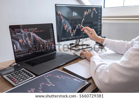 Stock exchange market concept, Business investor trading or stock brokers having a planning and analyzing with display screen and pointing on the data presented and deal on a stock exchange.