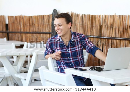 Successful attractive freelancer work on laptop computer in tropic cafe, stylish hipster use modern device