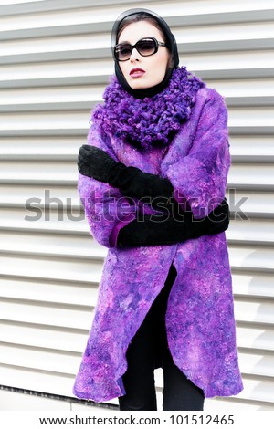 Stylish lady in bright purple coat in a city