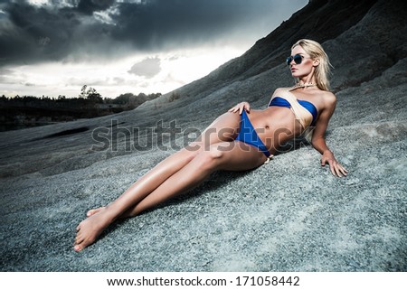 Young lady in bikini lying on sand rocks