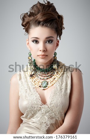 Young brunette lady with luxury accessories on gray background