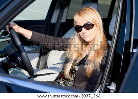 Young business lady in sunglasses sitting in a car