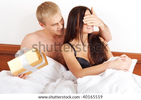 Young man presenting a gift to his girlfriend in bed