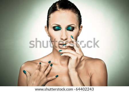 Portrait of beautiful lady showing blue nails isolated on grey in cross-process toning