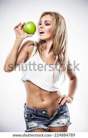 Sexy athletic woman shows orange in wet clothes on gray background