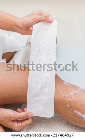 Woman removing hair from her legs and show fabric for waxing on two hand