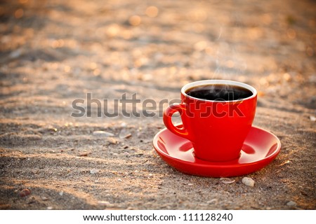 Red coffee cup on sand