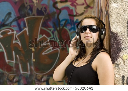 portrait of young woman with headphones at graffiti wall