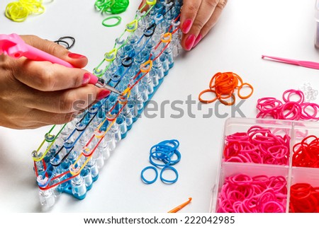 Young woman make rubber band bracelet with a loom