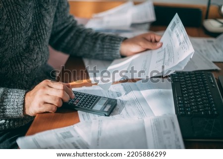 Close-up of male hands with a utility bill, a lot of checks and a calculator on the table. The man considers the costs of gas, electricity, heating. The concept of increasing tariffs for services Foto d'archivio © 