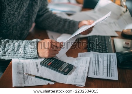 Close-up of male hands with a utility bill, a lot of checks and a calculator on the table. The man considers the costs of gas, electricity, heating. The concept of increasing tariffs for services Foto d'archivio © 