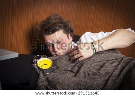 Man sleeping in bed with an alarm