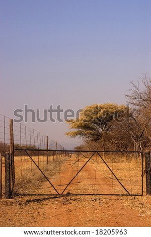 A gate dividing a game farm with bushveld in the background