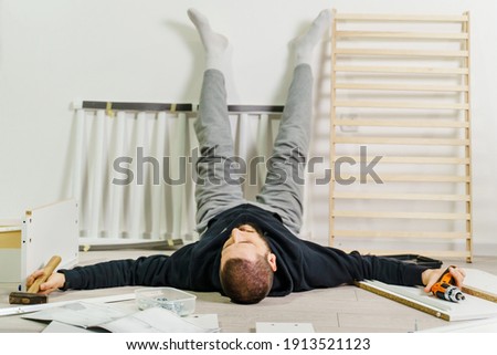 One man lying on the floor at home exhausted during self assembly project trying to put together DIY furniture devastated and desperate tired Foto stock © 