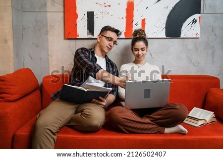 Man and woman young adult couple generation Z sitting together on the sofa bed at home study male and female friends helping each other with lesson tutor and student learning education concept Imagine de stoc © 