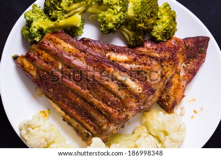 Grilled pork ribs meat with cooked cauliflower and broccoli on the withe plate
