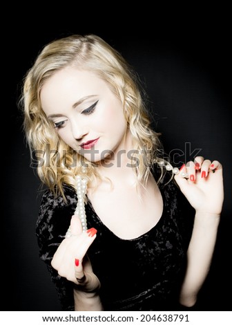 Portrait of attractive blond hair woman with vintage, classic hairstyle and makeup and pearls necklace in studio on the black background