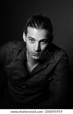 Portrait of young elegant man in the black shirt on the black background
