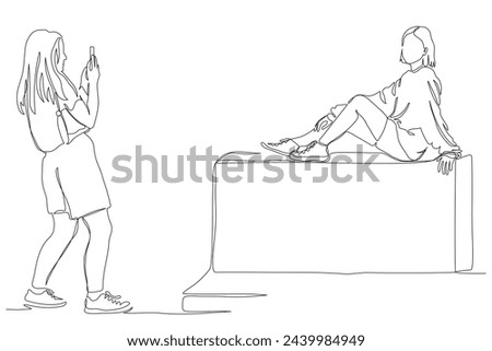 Young woman taking mobile picture of girlfriend sitting on stone. Photography. Continuous line drawing. Black and white vector illustration in line art style.
