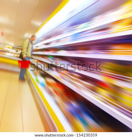 Blurred image of a man with a shopping basket in the grocery store.
