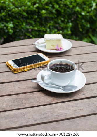 Coffee cake and phone on a wooden table, soft focus.